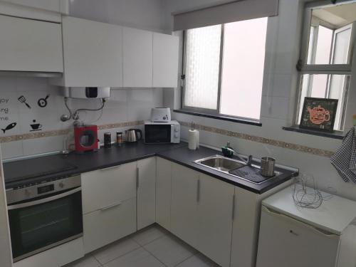 a kitchen with white cabinets and a sink at Reis Turismo in Faro