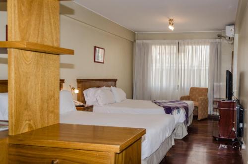 um quarto de hotel com duas camas e uma televisão em Altezza Apart Suites em Mendoza