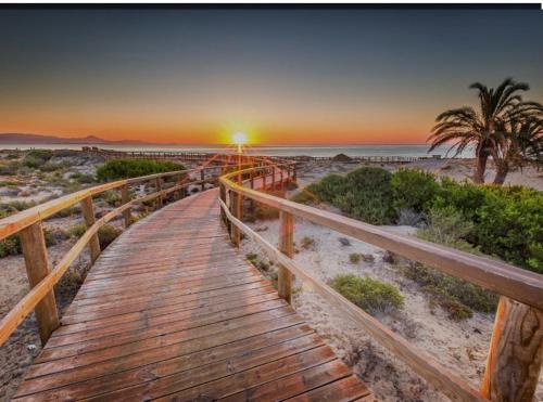un paseo marítimo de madera hasta la playa al atardecer en Brilliant Villa, en Gran Alacant