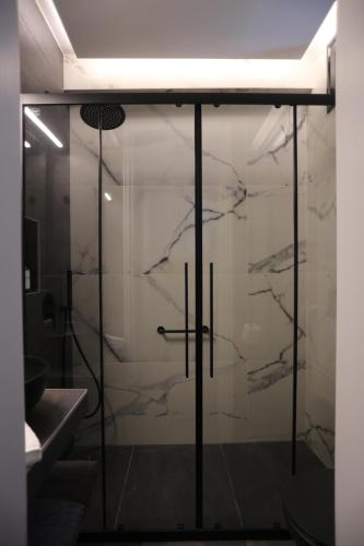 a bathroom with a glass door with a marble wall at Only2Suites in Athens