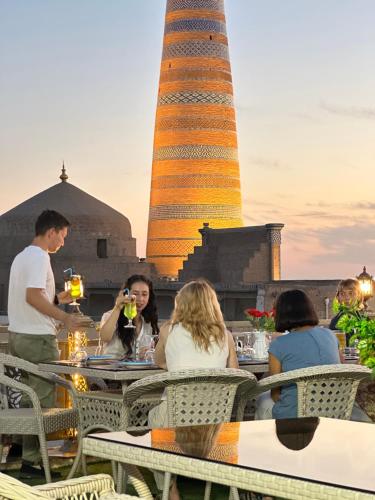 a group of people sitting at tables in front of a tower at New Minor Hotel in Khiva