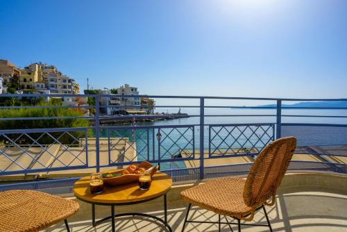 a table and chairs on a balcony with a view of the water at Asteria Seafront Luxury Apartment in Agios Nikolaos