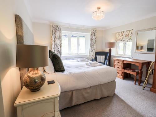 a bedroom with a bed and a table with a lamp at Fair Rigg in Sawrey