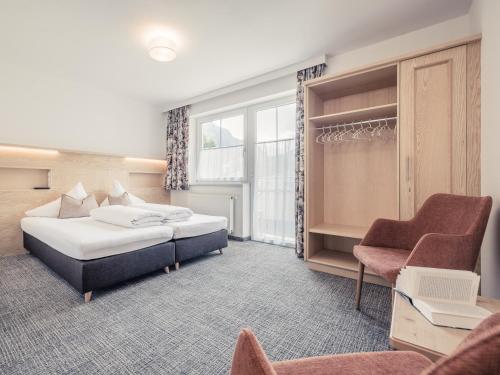 Pokój hotelowy z 2 łóżkami i krzesłem w obiekcie Tatte - Apartments w Solden