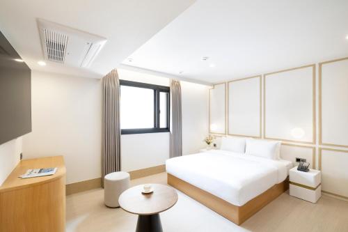 釜山にあるBusan H-AVENUE Hotel Seomyeon Stationの白いベッドとテーブルが備わるホテルルームです。