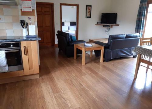 a living room with couches and a table and a kitchen at Heartsease Lodges in Llanddewi Ystradenny