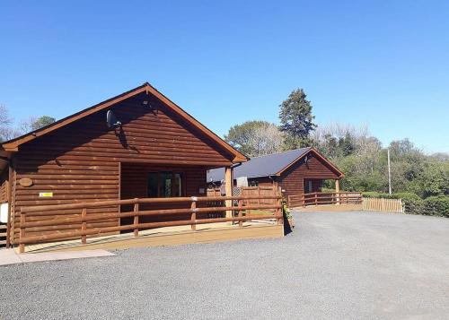 Heartsease Lodges في Llanddewi Ystradenny: كابينة خشب امامها سياج