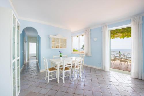 una sala da pranzo con tavolo e vista sull'oceano di Villa Rita Apartments a Massa Lubrense