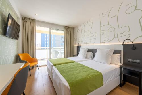 Cette chambre comprend un lit avec une couverture verte. dans l'établissement Benidorm Plaza, à Benidorm