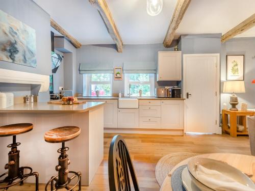 a kitchen with white cabinets and a counter with stools at Low Fold - Uk44733 in Tallentire