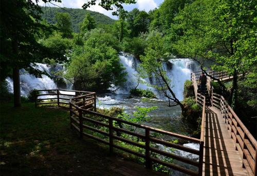 a bridge over a river with a waterfall in the background at Apartman Mely in Kulen Vakuf