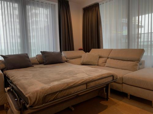 un ampio divano in un soggiorno con finestre di Stijlvol appartement in trendy wijk Oostende a Ostenda