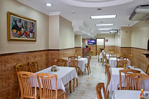 パナマシティにあるHotel Milan Panamaのダイニングルーム(白いテーブル、椅子付)