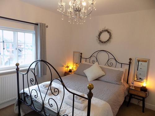 a bedroom with a bed and a chandelier at Double Award Winning, Stunning 1700's Grd 2 listed cottage near Stonehenge - Elegantly Refurbished Throughout in Amesbury