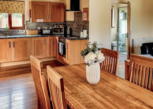 a kitchen with a table with a vase of flowers on it at Heartsease Lodges in Llanddewi Ystradenny
