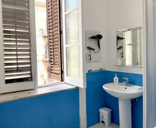 uma casa de banho azul e branca com um lavatório e uma janela em La casa del Maestro em Palermo