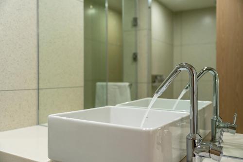 a white sink in a bathroom with a mirror at Busan H-AVENUE Hotel Seomyeon Station in Busan