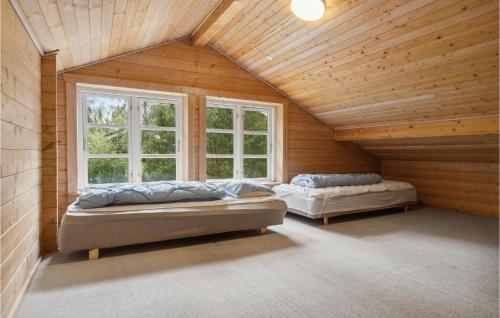 two beds in a room with wooden walls and windows at Pet Friendly Home In Kalundborg With Sauna in Kalundborg