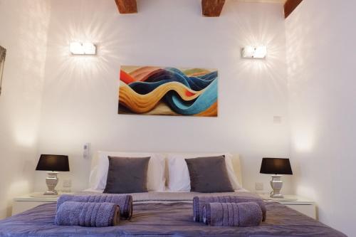 ein Schlafzimmer mit einem Bett mit zwei Lampen und einem Gemälde an der Wand in der Unterkunft SPQR Studios 2 Valletta in Valletta
