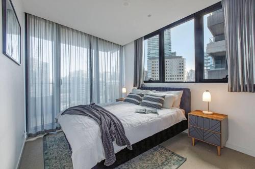 a bedroom with a bed and large windows at Premium Albert Park Grand Prix Apartment by Ready Set Host in Melbourne