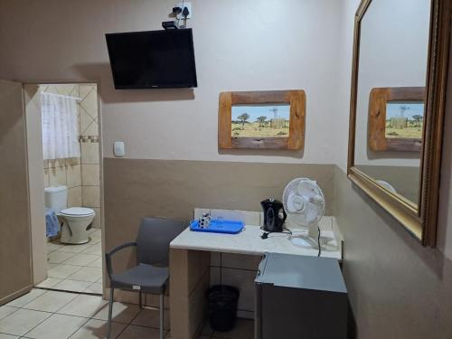 a bathroom with a desk with a fan and a mirror at Sleep 'n Go Guesthouse in Mokopane