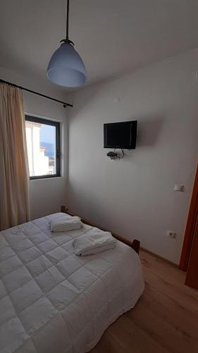 Schlafzimmer mit einem weißen Bett und einem Flachbild-TV in der Unterkunft ELISSOS APPARTMENT MONEMVASIA in Yéfira