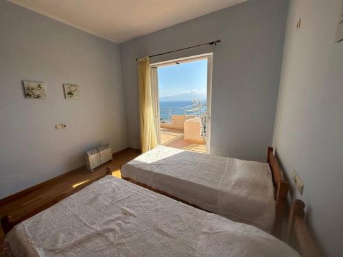 a bedroom with two beds and a large window at Sea view Sarande in Sarandë