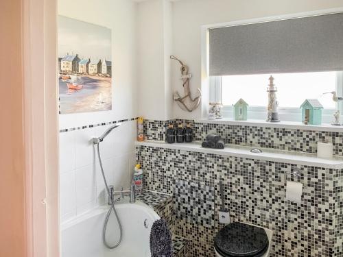 baño con lavabo y aseo y ventana en Sunny Prestatyn Apartment, en Prestatyn