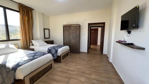 a hotel room with two beds and a flat screen tv at Al-jabal castle Hotel - Ajloun in Ajloun