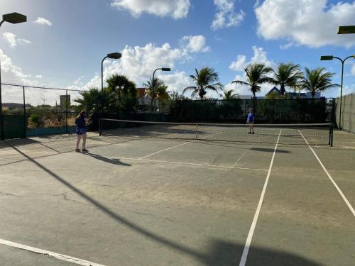 zwei Personen, die Tennis auf einem Tennisplatz spielen in der Unterkunft Sand Dollar Bonaire in Kralendijk