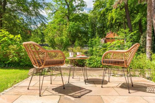two rattan chairs and a table in a garden at Pineblue Villas in Heringsdorf