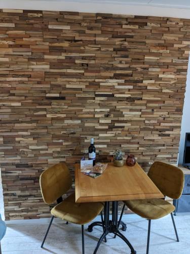 a wooden table with two chairs in front of a brick wall at zomerhuis in Wijk aan Zee! 2 pers in Wijk aan Zee
