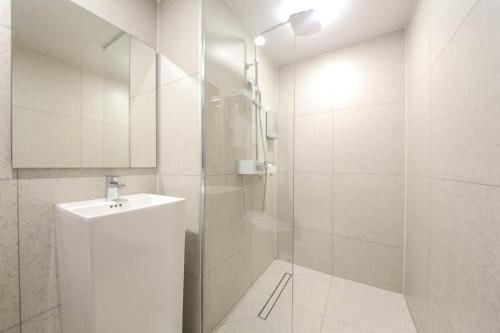 a white bathroom with a shower and a sink at Busan H-AVENUE Hotel Seomyeon Station in Busan