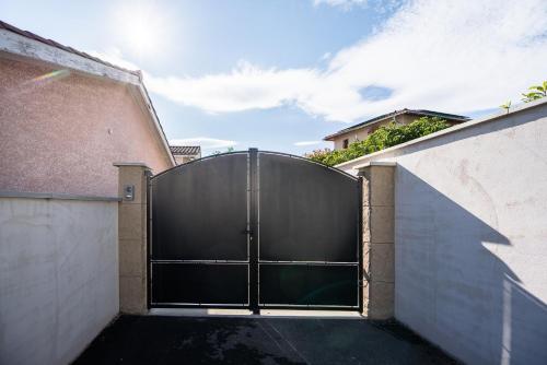 une grande porte de garage noir sur le côté du bâtiment dans l'établissement Le Petit Saugnieu, à Colombier-Saugnieu