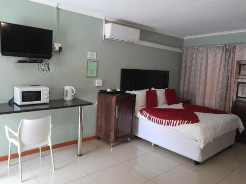 a bedroom with a bed and a desk with a microwave at RS GARDEN GUESTHOUSE in Thohoyandou