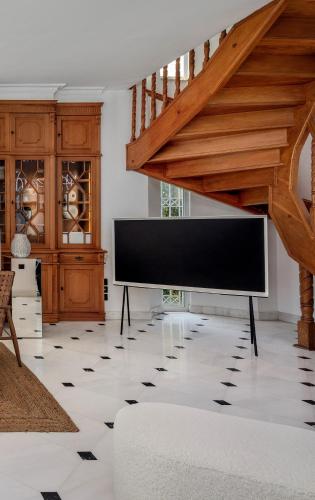a living room with a large television and a staircase at The Southern Mansion Athens in Athens