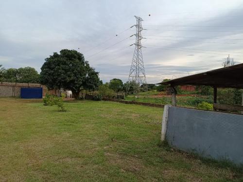 um campo com uma torre de transmissão de electricidade à distância em Chacara Tropicalia em Passos