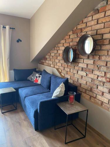 uma sala de estar com um sofá azul e uma parede de tijolos em Apartament Młyńska em Augustów