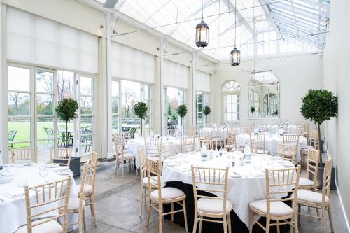 a room with white tables and chairs and windows at Buxted Park Country House in Buxted