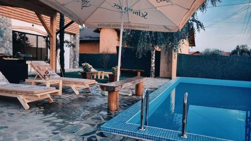 a patio with a pool and an umbrella and a table at CASA DE VACANTA CLARA MARIA in Comarnic