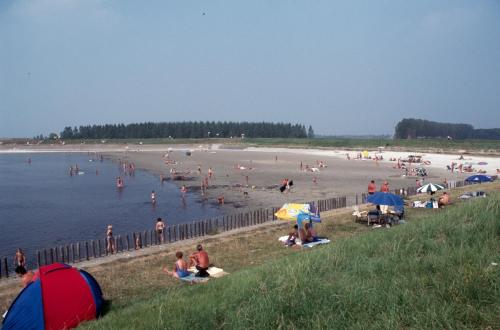 a group of people on a beach with people in the water at Luxe Recreatie Bungalow NO 10 in Scherpenisse