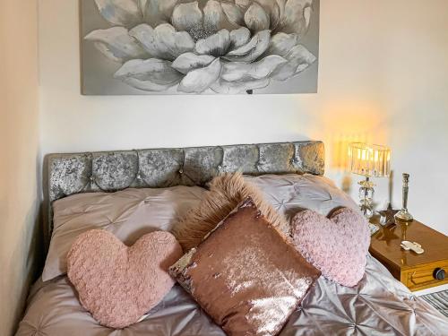 1 cama con 2 almohadas para el corazón y una foto en la pared en Sunny Rhyl Apartment - Uk44631, en Rhyl