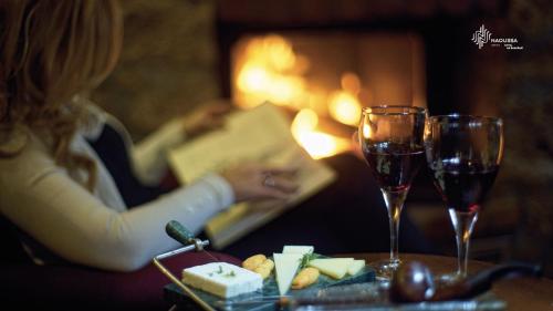 a woman sitting at a table with a book and wine glasses at Εσπερίδες in Naousa Imathias