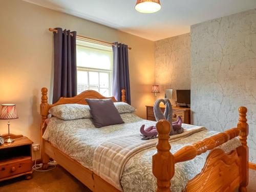 a bedroom with a bed with a wooden frame and a window at Estate Cottage in Wheldrake