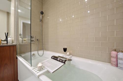 a bathroom with a bath tub with a glass shower at Luxury 1 bed flat, minutes from Canary Wharf and South Quay Station in London