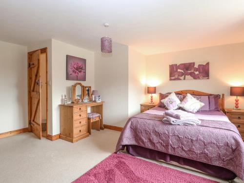 a bedroom with a bed with a purple bedspread at 2 Stud Cottage in Hainford