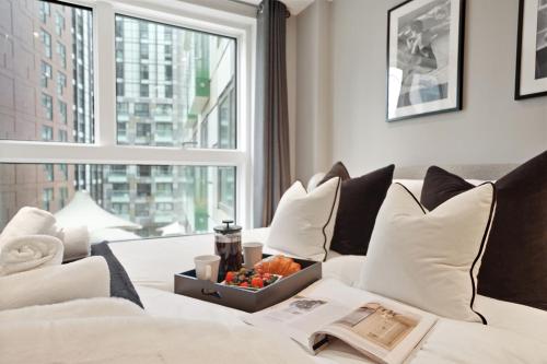 a hotel room with a bed with a tray of fruit on it at Luxury 1 bed flat, minutes from Canary Wharf and South Quay Station in London