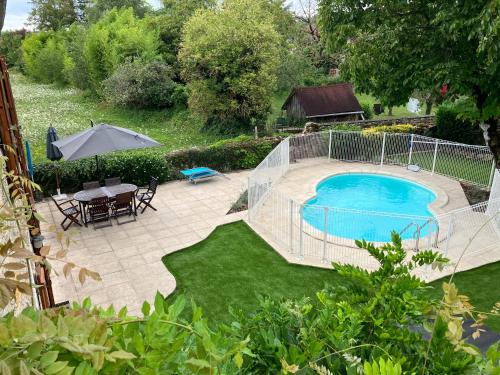 une cour avec une piscine, une table et un parasol dans l'établissement La Grange Du Noyer, à Cornac