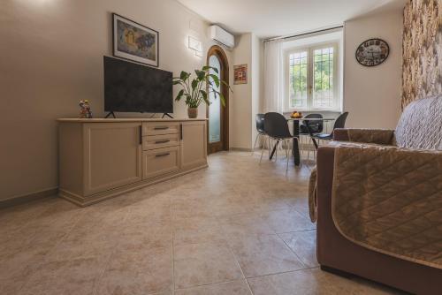 a living room with a tv on a cabinet and a dining room at Casa Dolce Casa in Orvieto