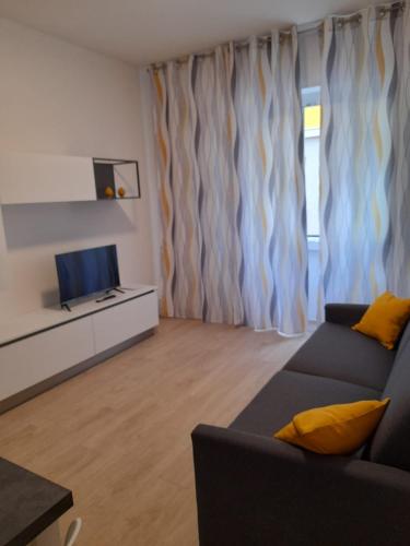 a living room with a couch and a television at Bike & Family Hotel Derby in Finale Ligure